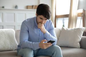 man staring at smartphone on couch