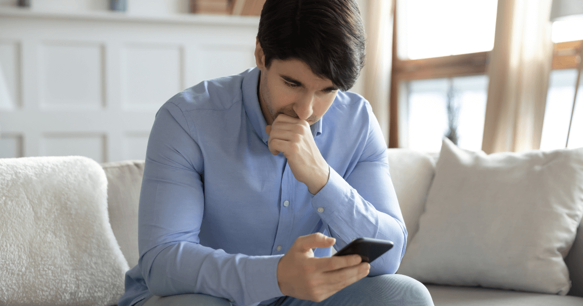 man staring at phone on couch