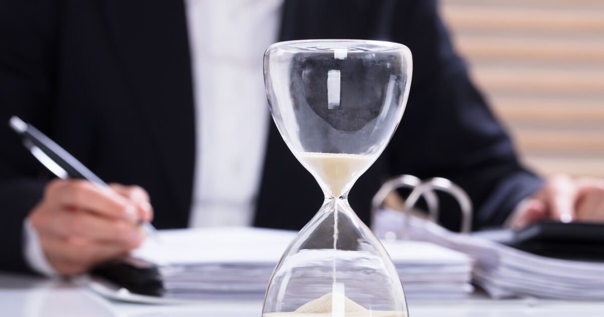 hourglass on table with person completing documents