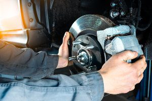 mechanic working on vehicle brakes