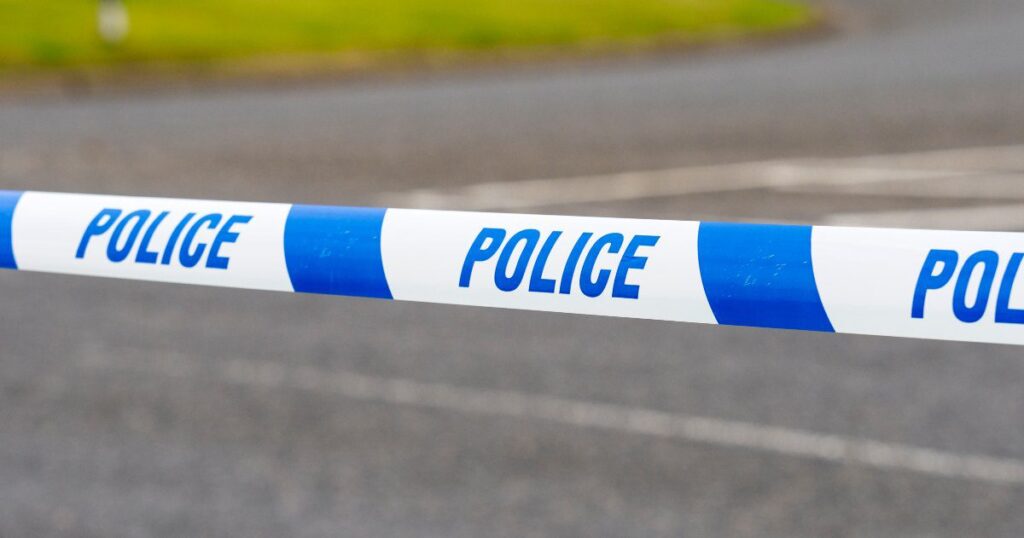 Police "do not cross line" across a road in daylight