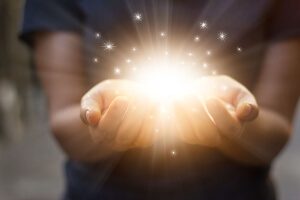 two hands holding a bright light to illustrate giving back