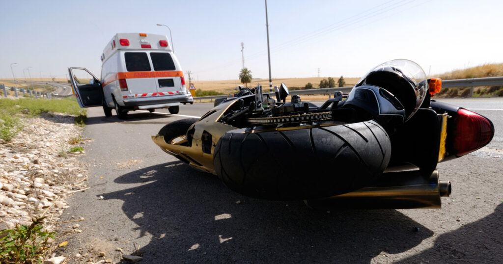 image of crashed motorcycle with an ambulance in the background
