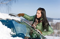 female driver clearing her window of snow
